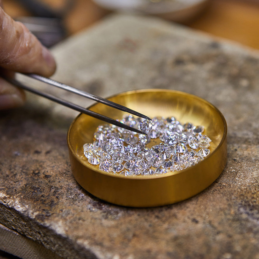 A hand picks up a diamond to see the difference between a moissanite vs. lab diamond