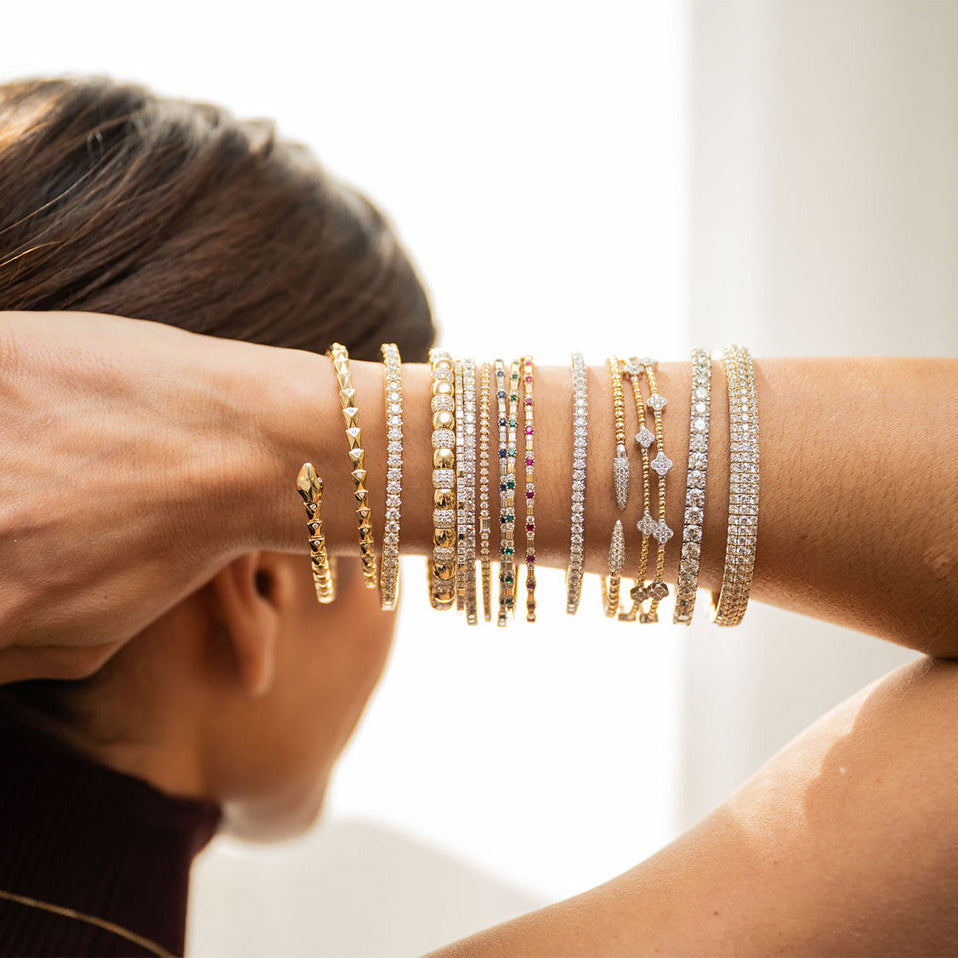 Rear close up view of a woman with her arms behind her head, displaying several bangles on her arm