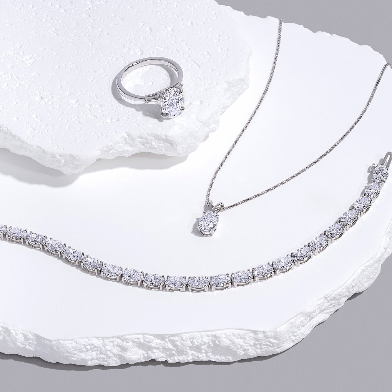 Tennis bracelet, diamond pendant necklace, and diamond ring symbolizing IGI vs GIA diamond certification