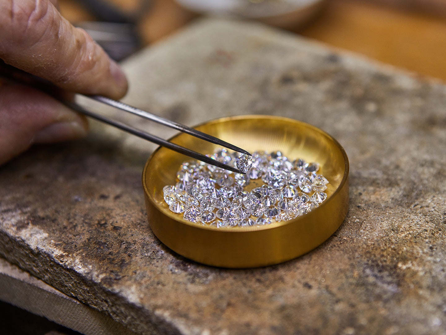 A hand picks up a diamond to see the difference between a moissanite vs. lab diamond