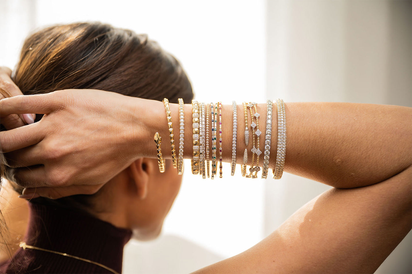 Rear close up view of a woman with her arms behind her head, displaying several bangles on her arm