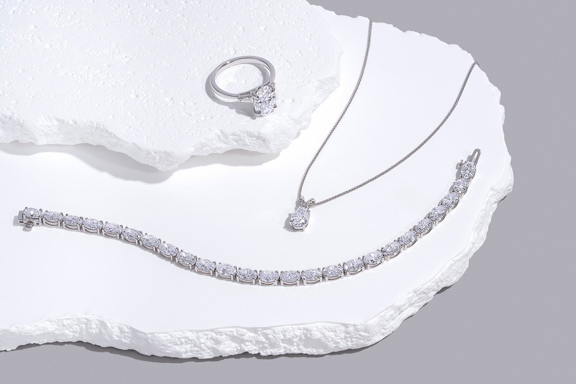 Tennis bracelet, diamond pendant necklace, and diamond ring symbolizing IGI vs GIA diamond certification